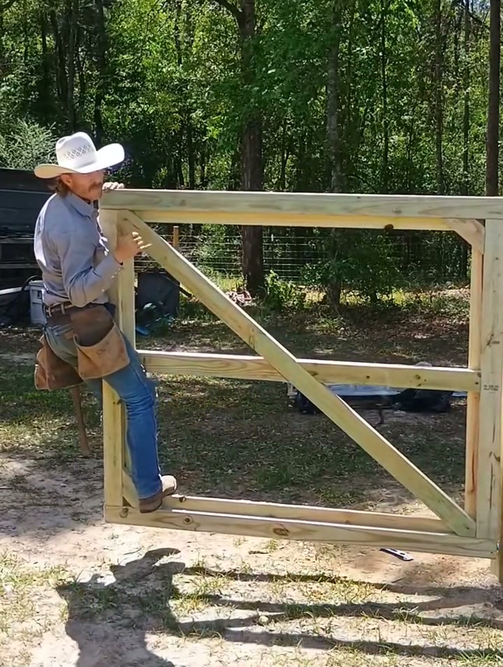 Grant Pruett swinging closed a hand-built wooden farm gate